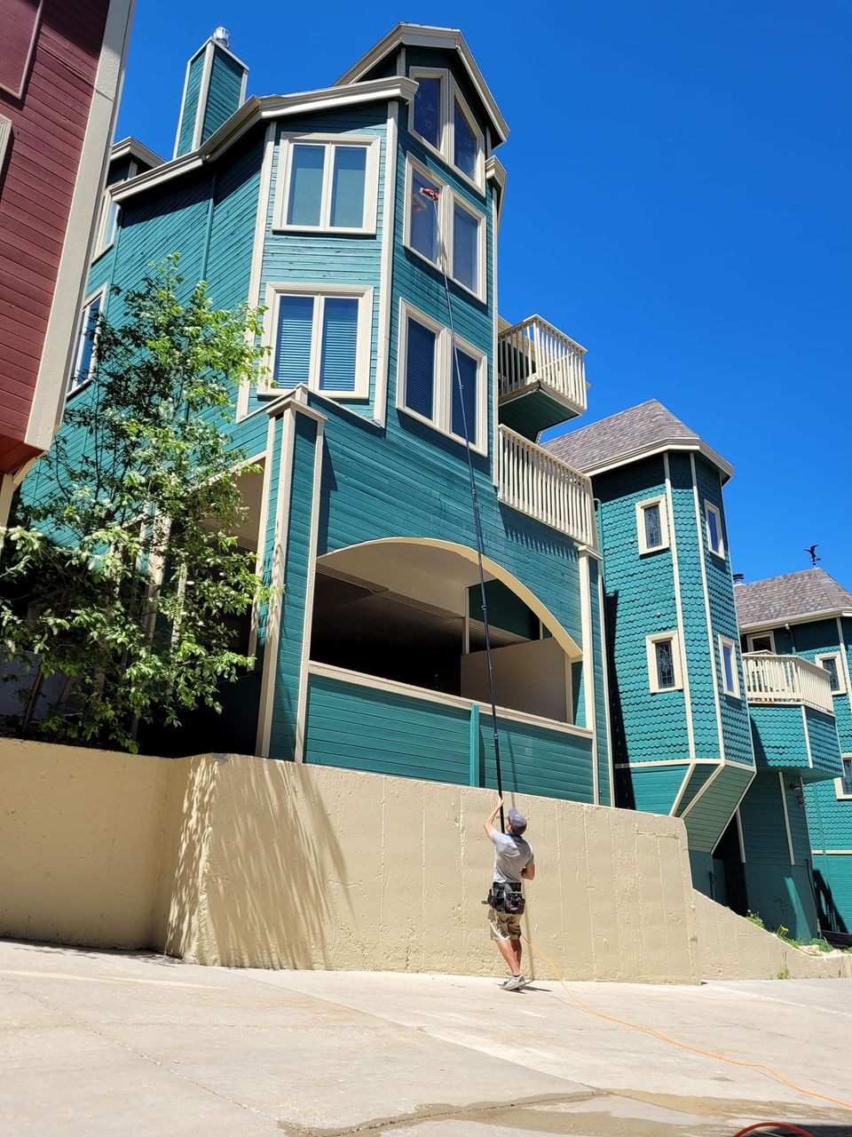 a tall waterfed pole is being used to wash windows on the 4th floor of this massive home